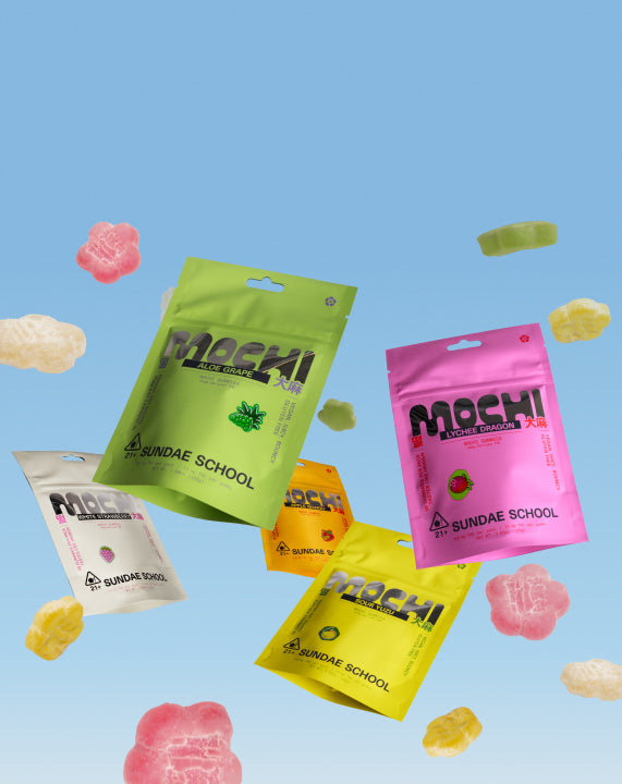 Horizontal promotional banner displaying five colorful pouches of Sundae School Mochi Gummies arranged across a sky-blue background alongside floating flower-shaped gummies. Flavors shown include White Strawberry, Aloe Grape, Apple Mango, Sour Yuzu, and Lychee Dragon.