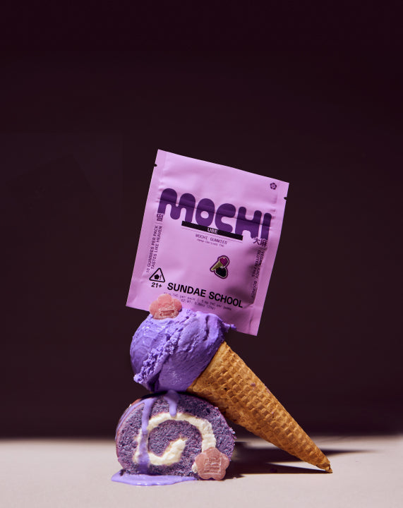 Sundae School 5mg 10-pack Ube mochi and its packaging stacked on top of melting ube ice cream on a cone stacked on a ube roll cake against a dark purple background.