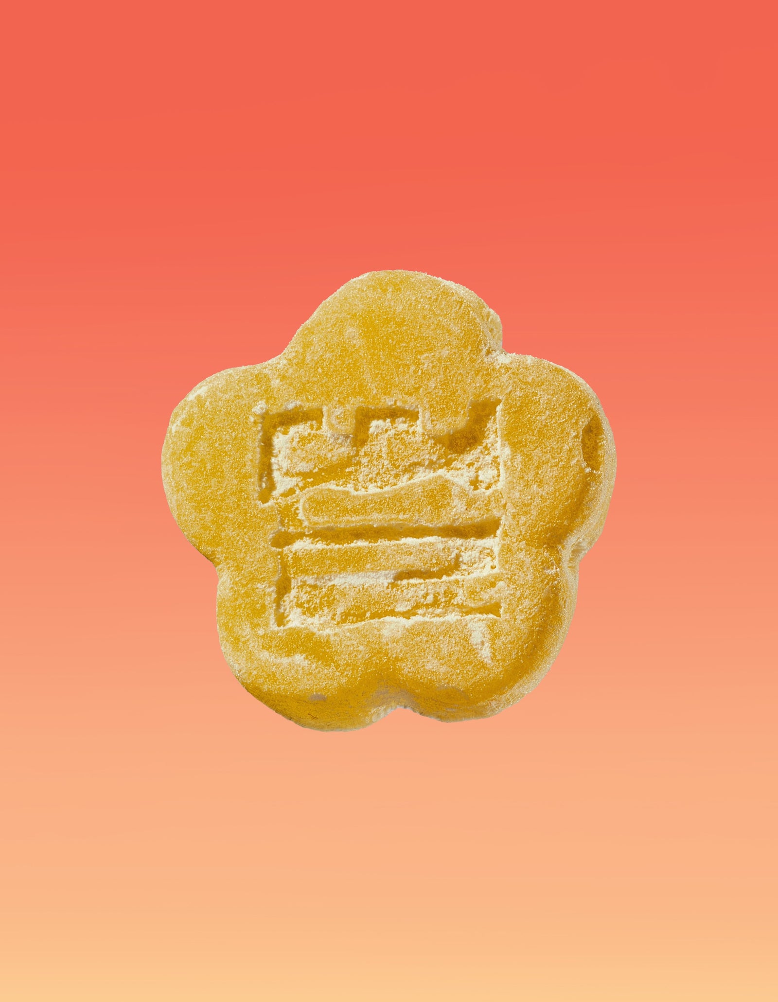 An image of a Kimchee Yuzu gummy on a gradient background going pink to yellow. 