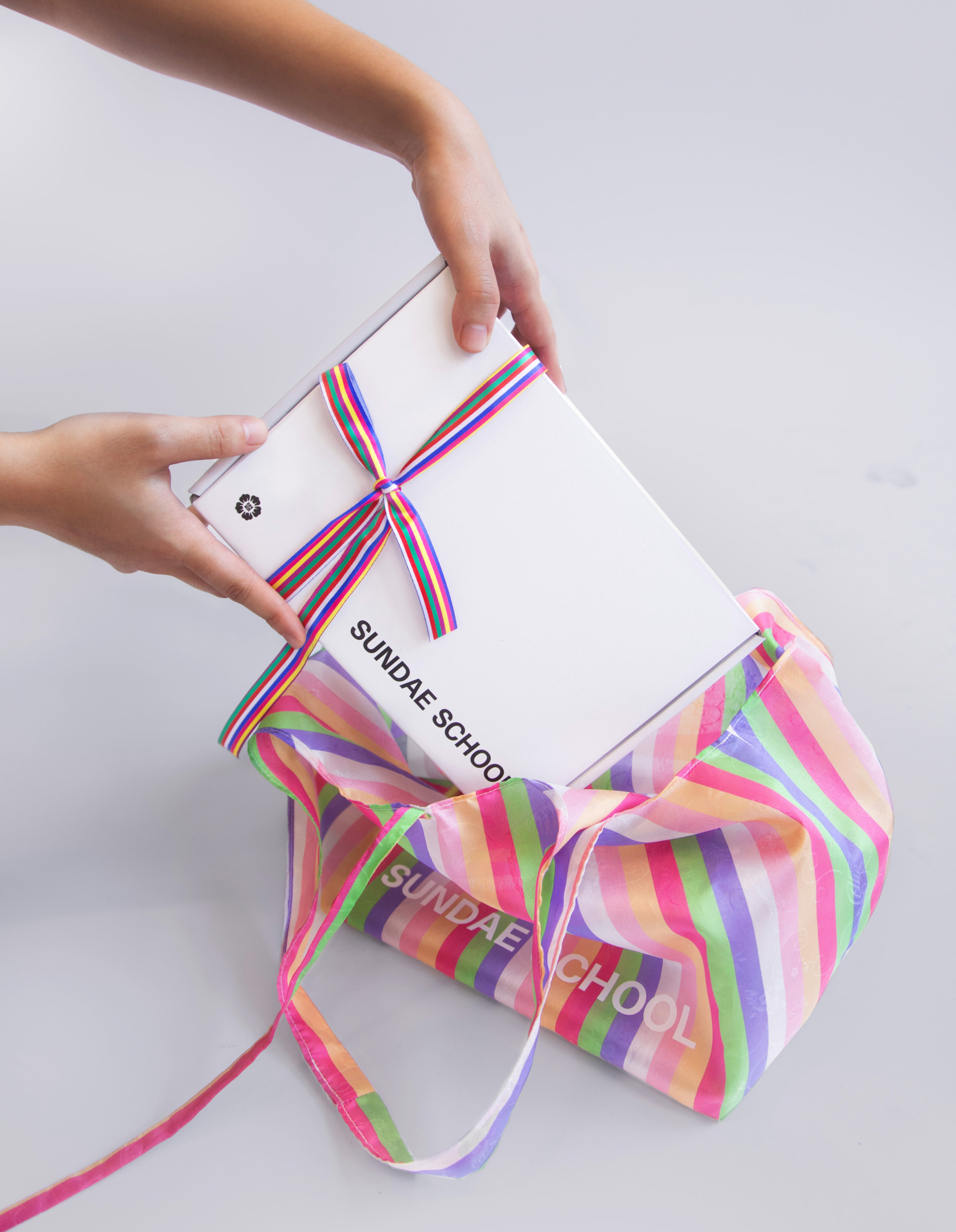 An image of hands pulling a Sundae School gift box out of Sundae School mini bojagi bag.
