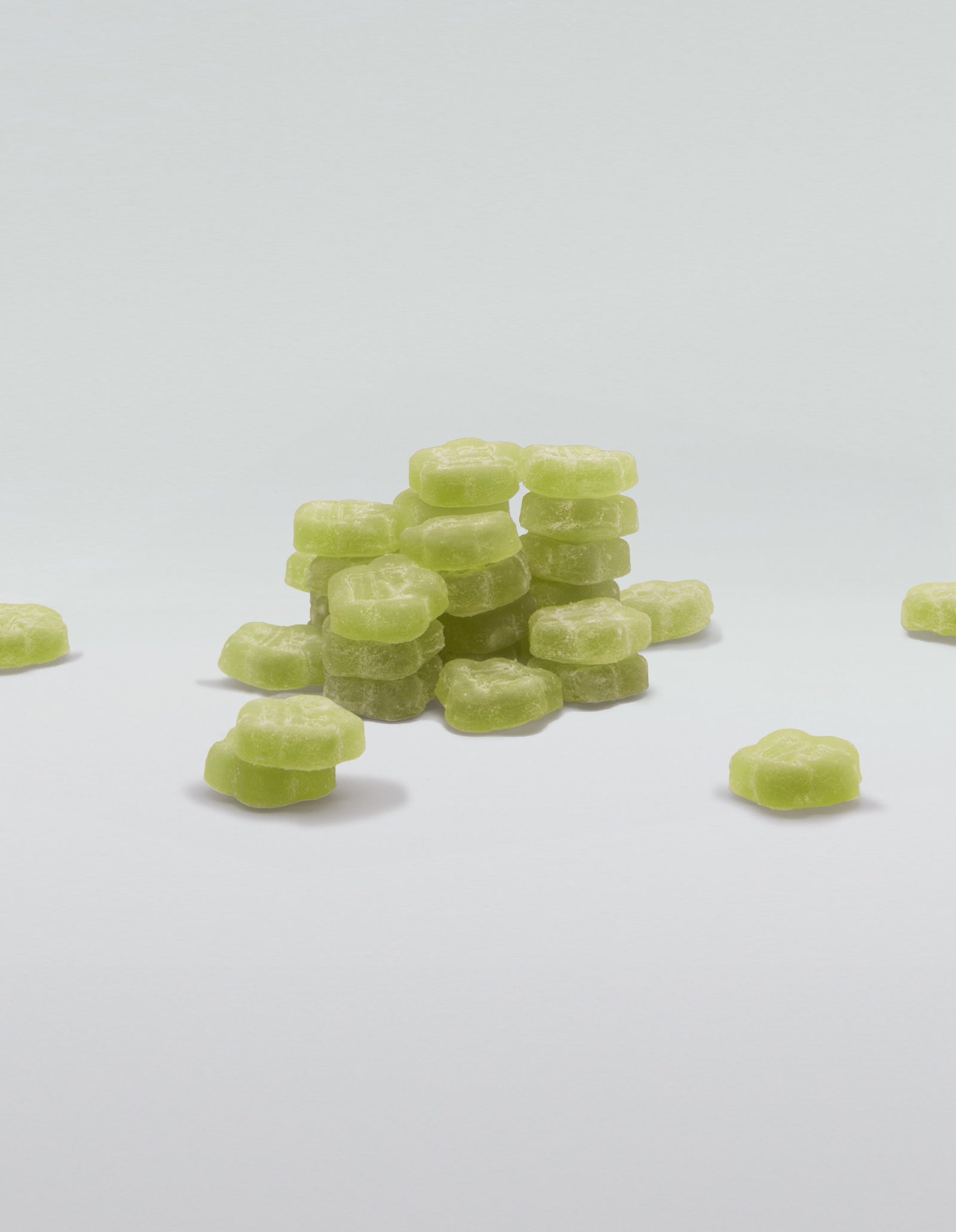 An image of a pile of Aloe Grape gummies stacked and scattered on a white surface.
