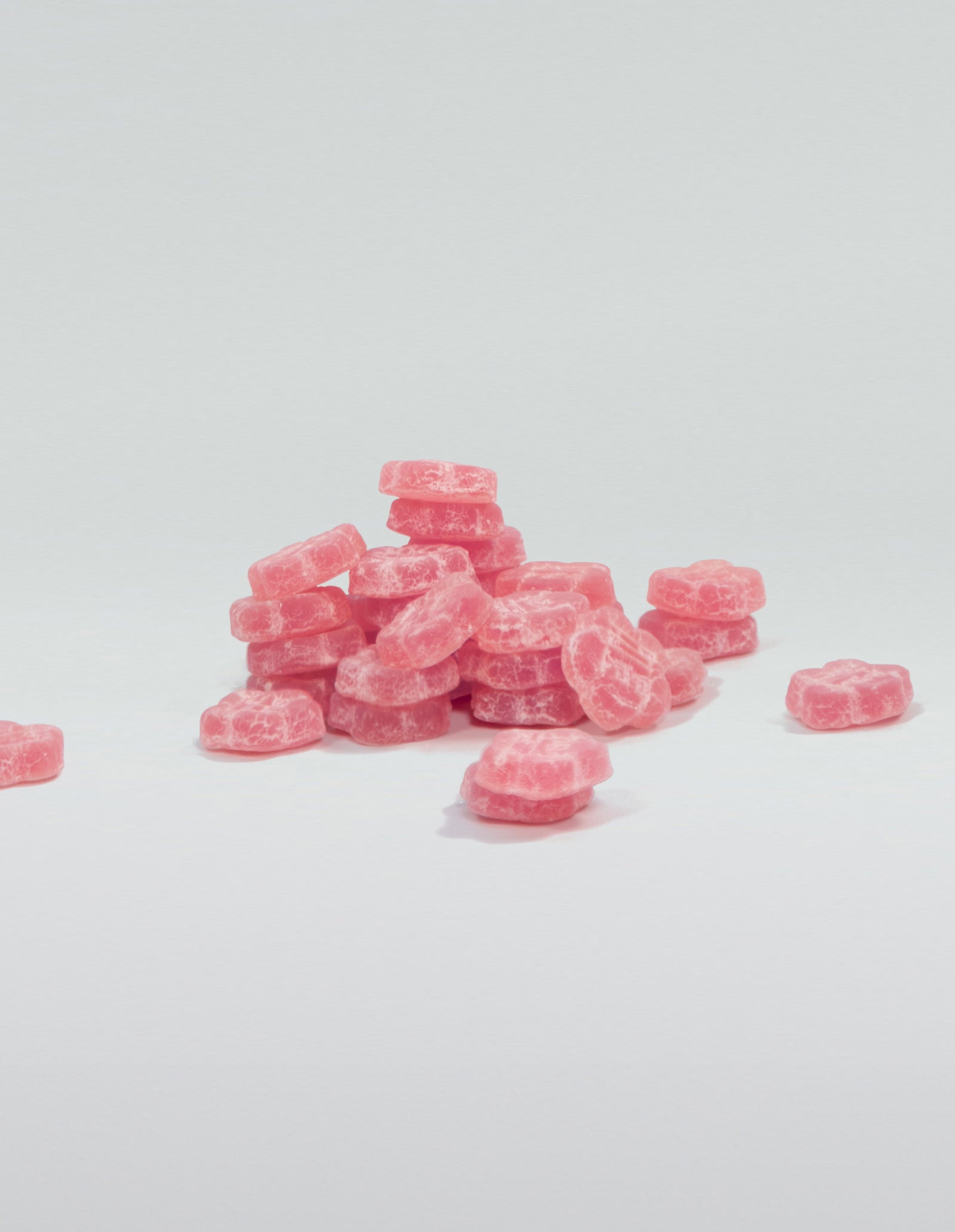 An image of a pile of lychee dragon gummies stacked and scattered on a white surface. 