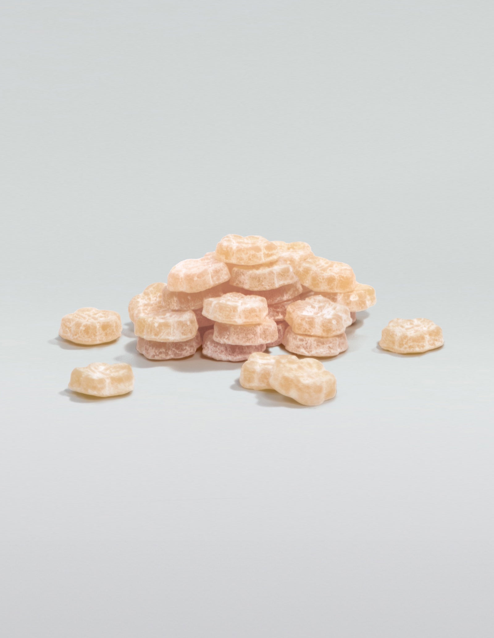 An image of a pile of White Strawberry gummies stacked and scattered on a white surface.