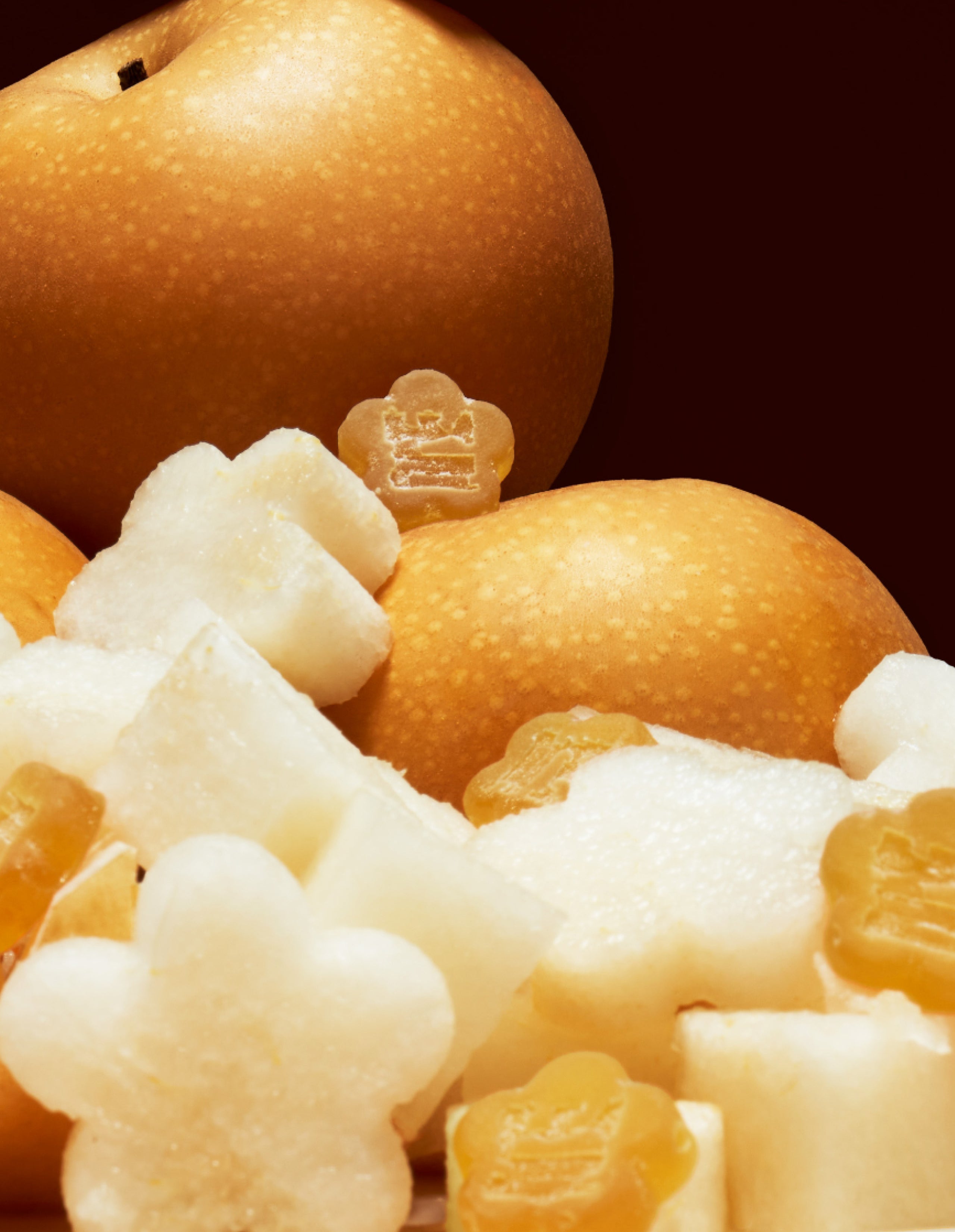 Collection of cut pear in the shape of flowers alongside Sundae School Golden Pear mochi gummies and whole korean pears