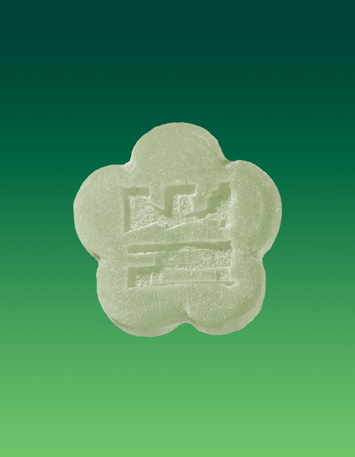 An image of an aloe grape gummy on a gradient background going dark green to light green. 
