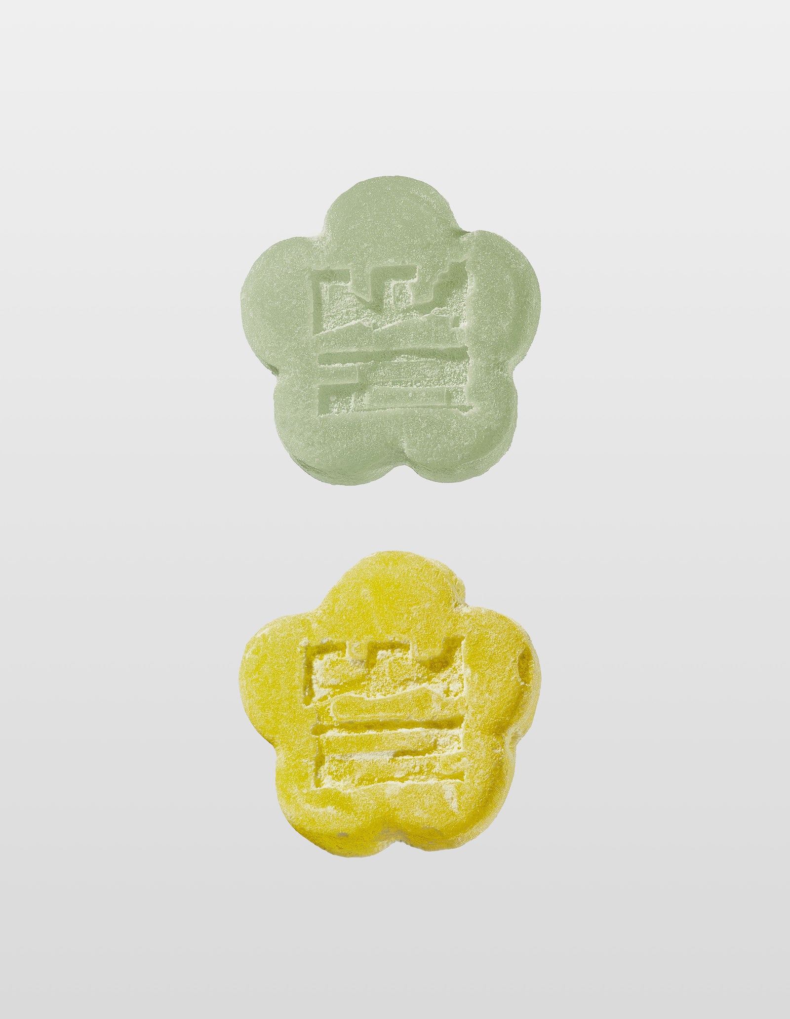 Two Mochi gummies are shown vertically against a white background. The top gummy is Aloe Grape and the bottom is Sour Yuzu, both with an embossed design of the companies logo 'Ddul' spelt out in Korean. 