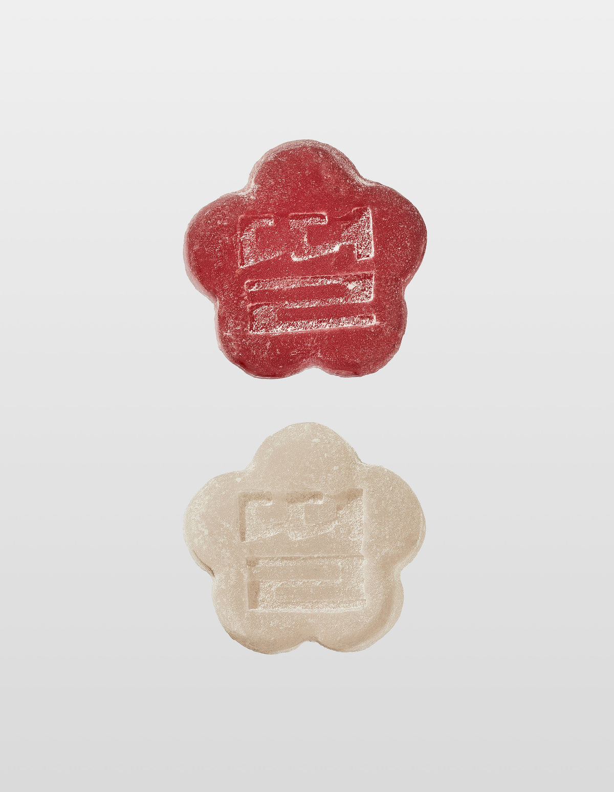 Two Mochi gummies are shown vertically against a white background. The top gummy is Slumber Berry and the bottom is White Strawberry, both with an embossed design of the companies logo 'Ddul' spelt out in Korean. 