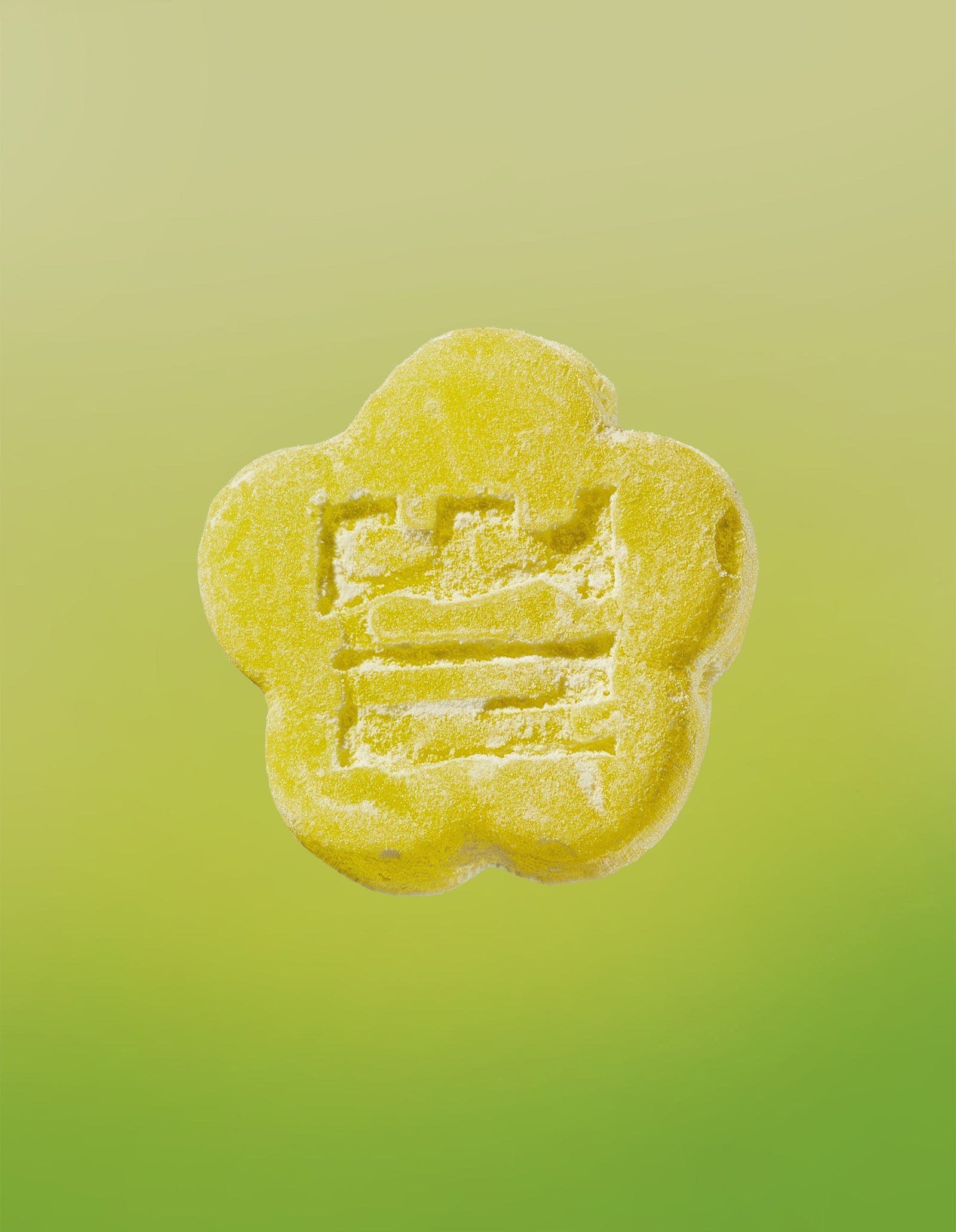 An image of a Sour Yuzu gummy on a gradient background going yellow to lime green. 