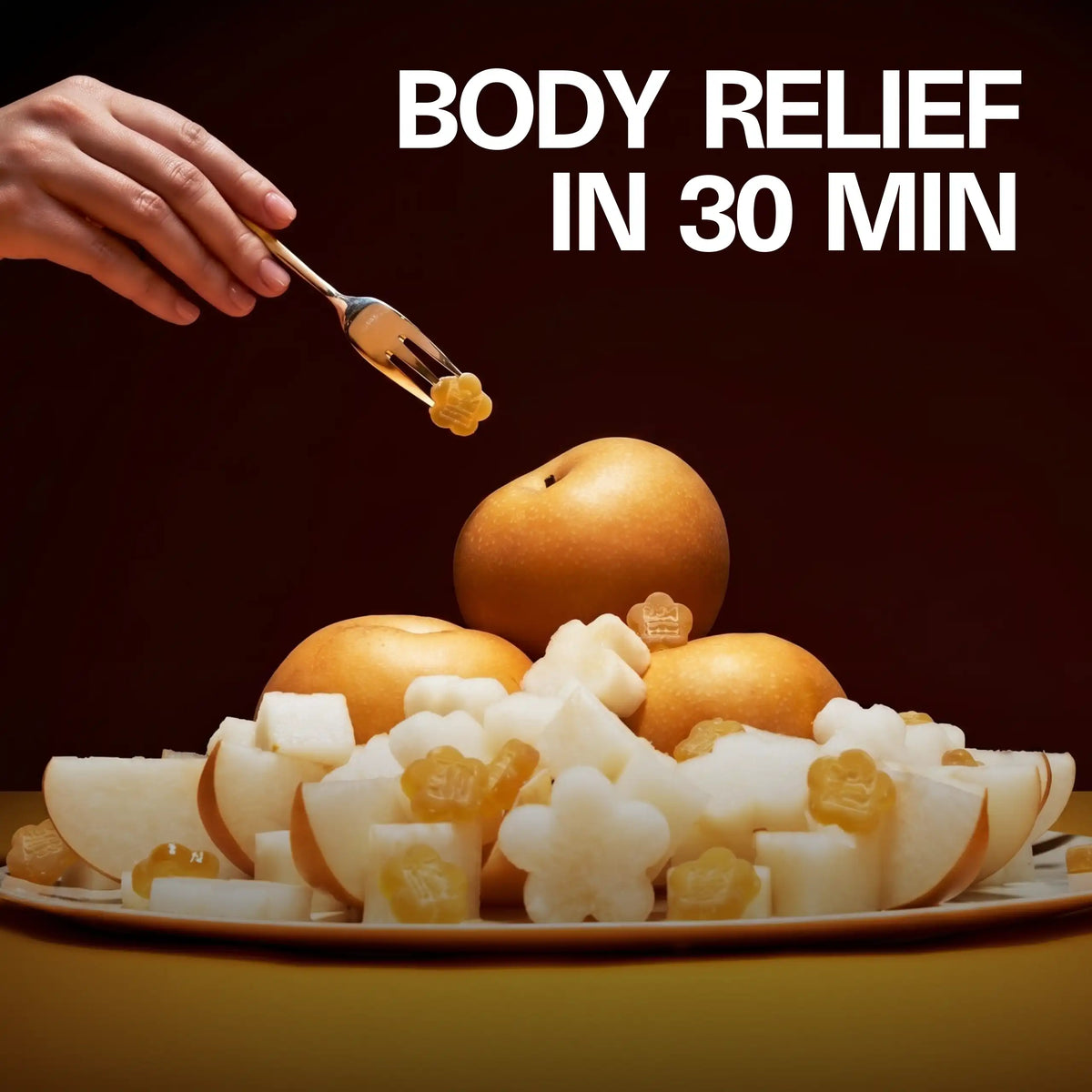 Lifestyle shot of a flower-shaped Sundae School Mochi Golden Pear gummy with whole and cut golden pear fruit, with the headline 'Body Relief in 30 Min'