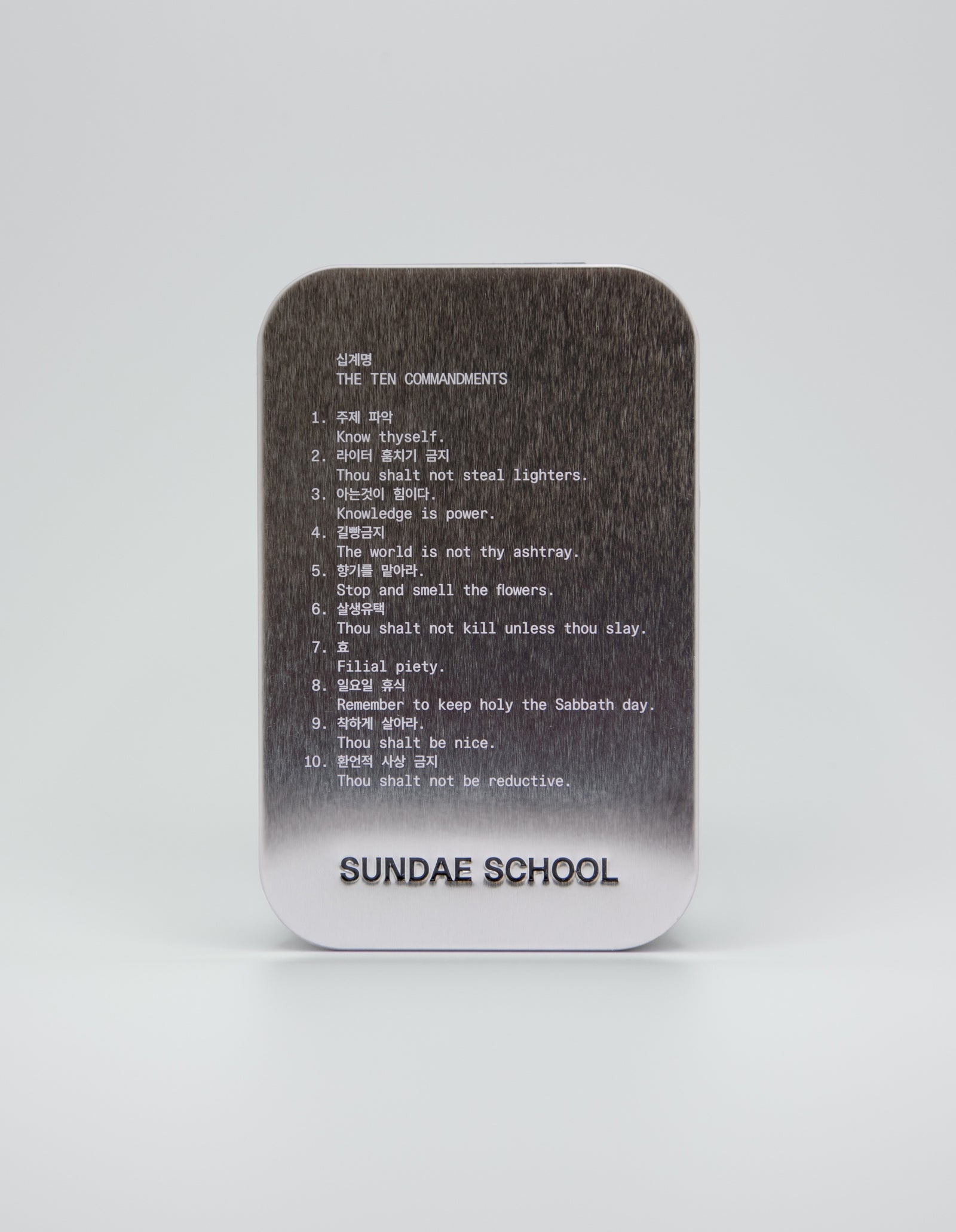 An image of a tin that houses the gummies with the companies 10 commandments:
1. Know Thyself.
2. Thou shalt not steal lighters.
3. Knowledge is power.
4. The world is not thy ashtray.
5. Stop and smell the flowers.
6. Thou shalt not kill unless thou slay.
7. Filial piety.
8. Remember to keep holy the Sabbath day.
9. Thou shalt be nice.
10. Thou shalt not be reductive. 
with a embossment of their company name at the bottom of the tin "Sundae School".