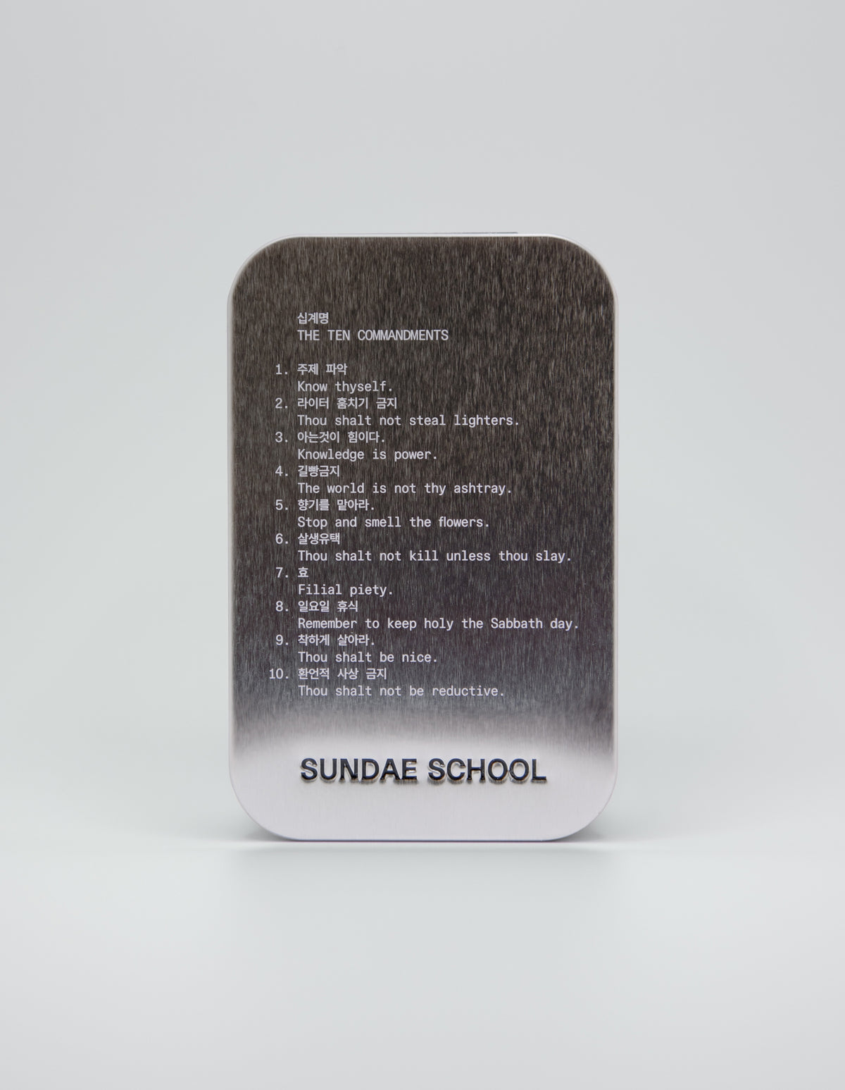 An image of a tin that houses the gummies with the companies 10 commandments:
1. Know Thyself.
2. Thou shalt not steal lighters.
3. Knowledge is power.
4. The world is not thy ashtray.
5. Stop and smell the flowers.
6. Thou shalt not kill unless thou slay.
7. Filial piety.
8. Remember to keep holy the Sabbath day.
9. Thou shalt be nice.
10. Thou shalt not be reductive. 
with a embossment of their company name at the bottom of the tin "Sundae School".