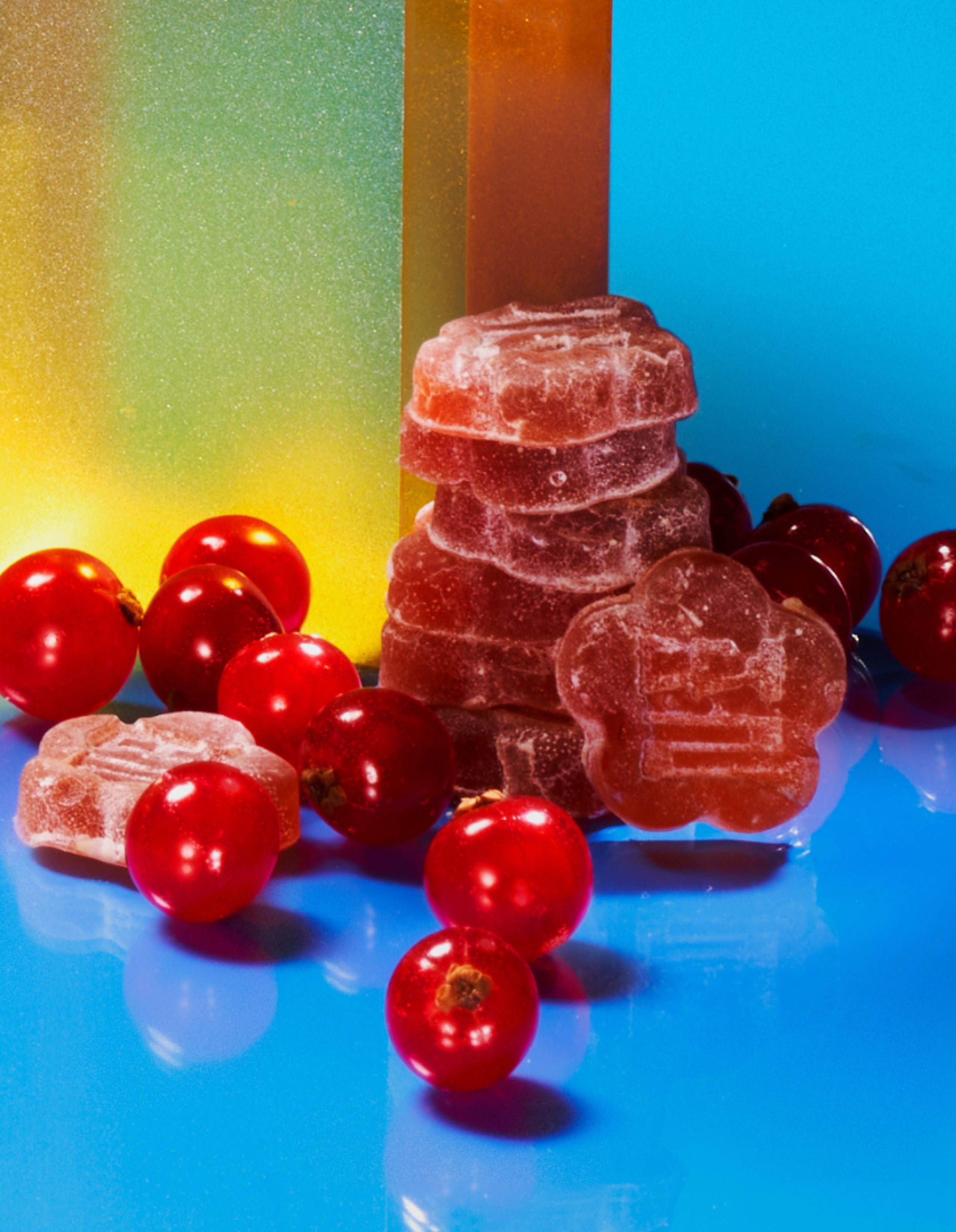 Sundae School Slumberberry mochi gummies stacked next to fresh omjia (Korean Magnolia Berries) on colorful background