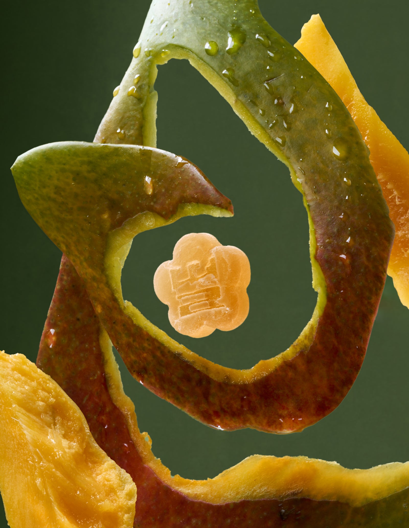 Sundae School Apple Mango mochi gummy suspended in curled mango peel against green background