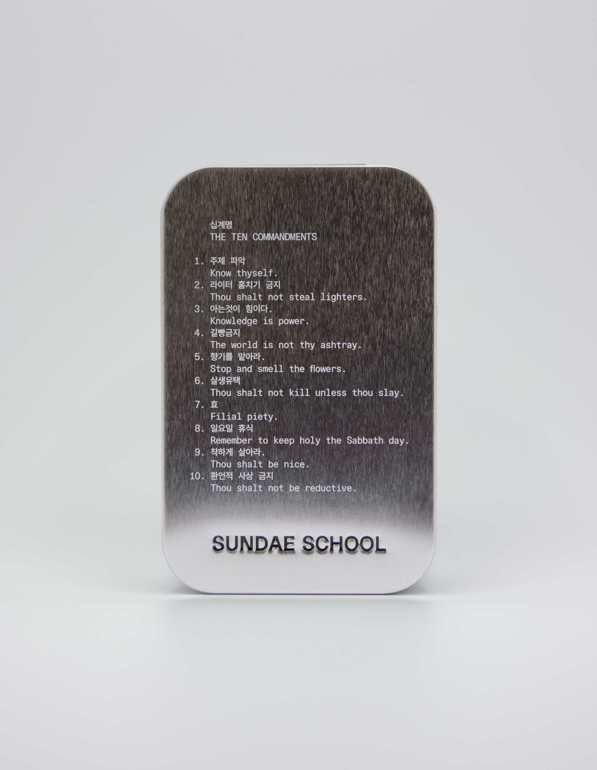 An image of a tin that houses the gummies with the companies 10 commandments:
1. Know Thyself.
2. Thou shalt not steal lighters.
3. Knowledge is power.
4. The world is not thy ashtray.
5. Stop and smell the flowers.
6. Thou shalt not kill unless thou slay.
7. Filial piety.
8. Remember to keep holy the Sabbath day.
9. Thou shalt be nice.
10. Thou shalt not be reductive. 
with a embossment of their company name at the bottom of the tin "Sundae School".