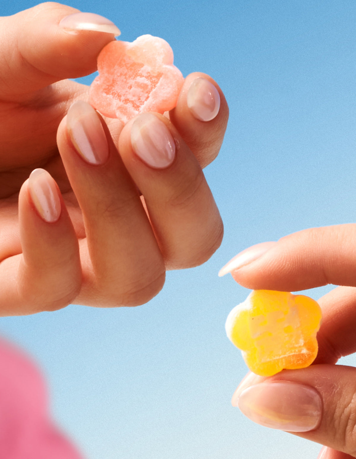 Two hands holding mochi gummies in hand against a blue background