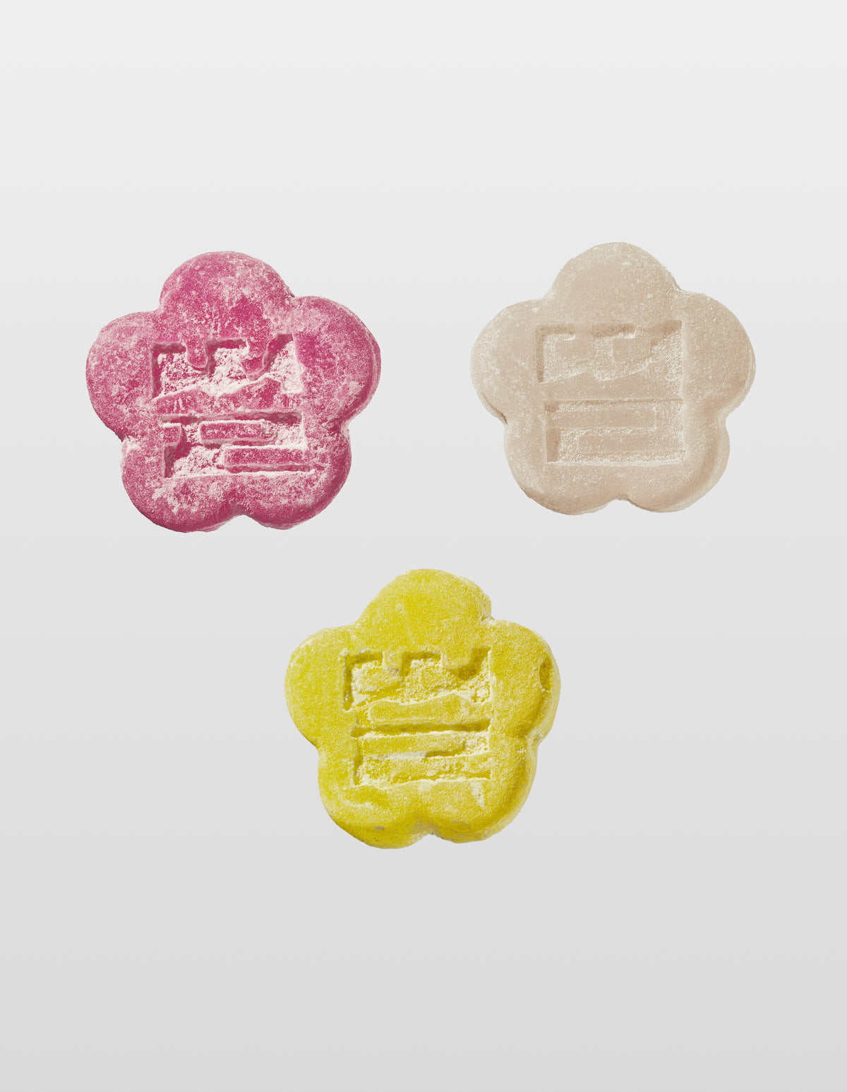Three colorful  flower-shaped Mochi Gummies in Red, White, Yellow on a white background