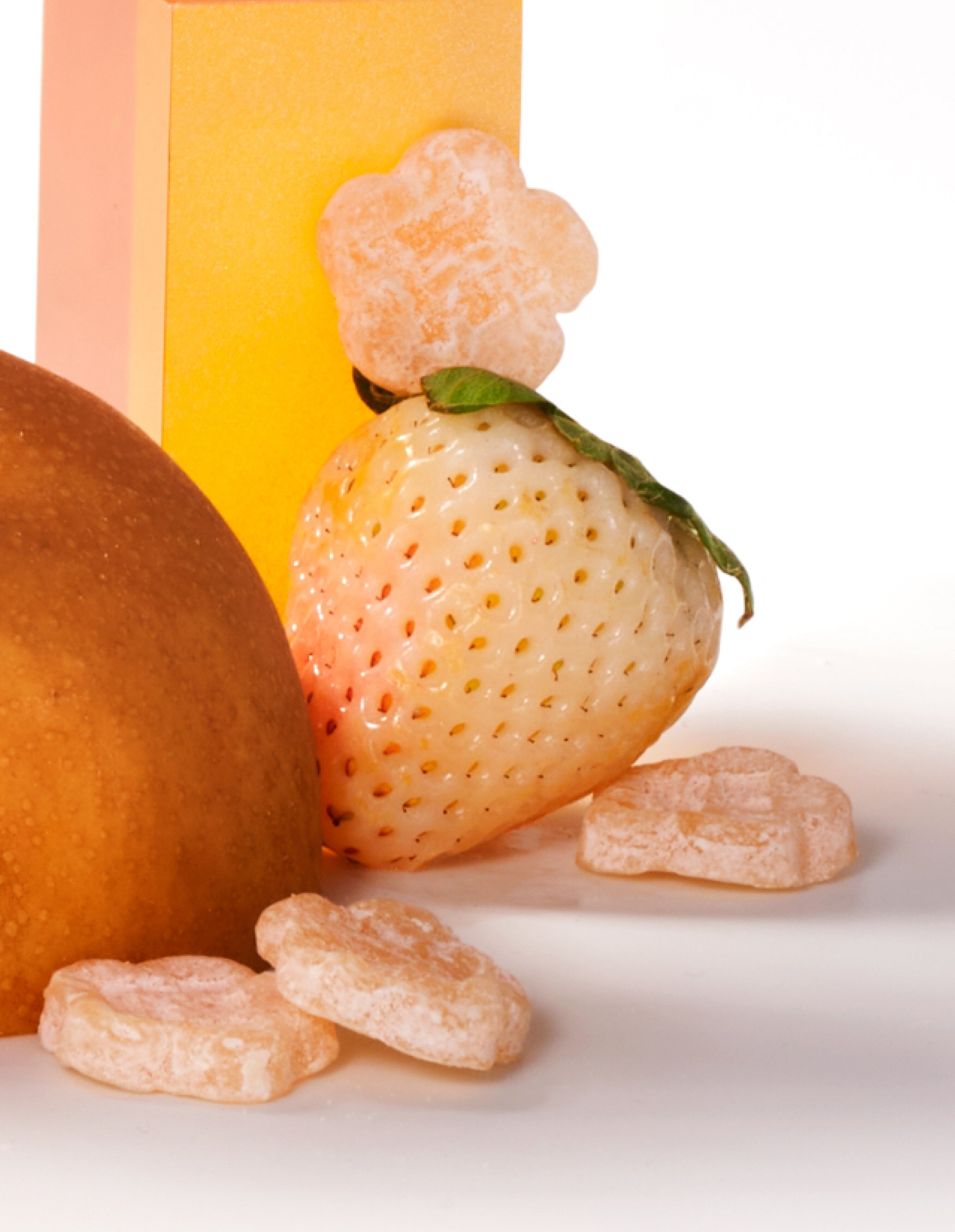 Sundae School White Strawberry Mochi gummies laid around a white strawberry fruit against a white background