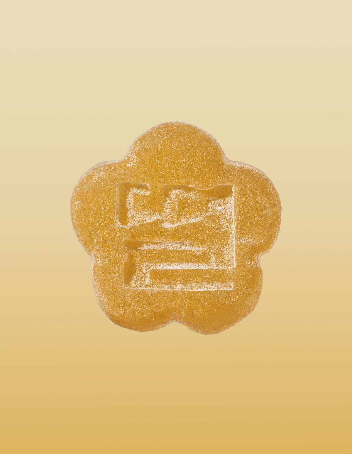 An image of a golden pear gummy on a gradient background going light yellow to brownish-orange. 